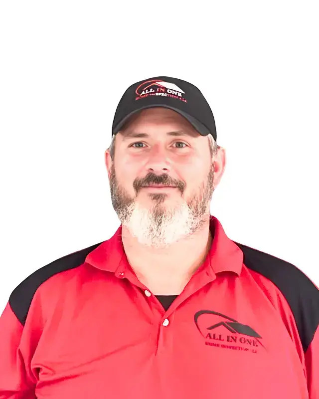A man with a beard wearing a black cap and a red polo shirt with ALL IN ONE logo, standing against a white background.